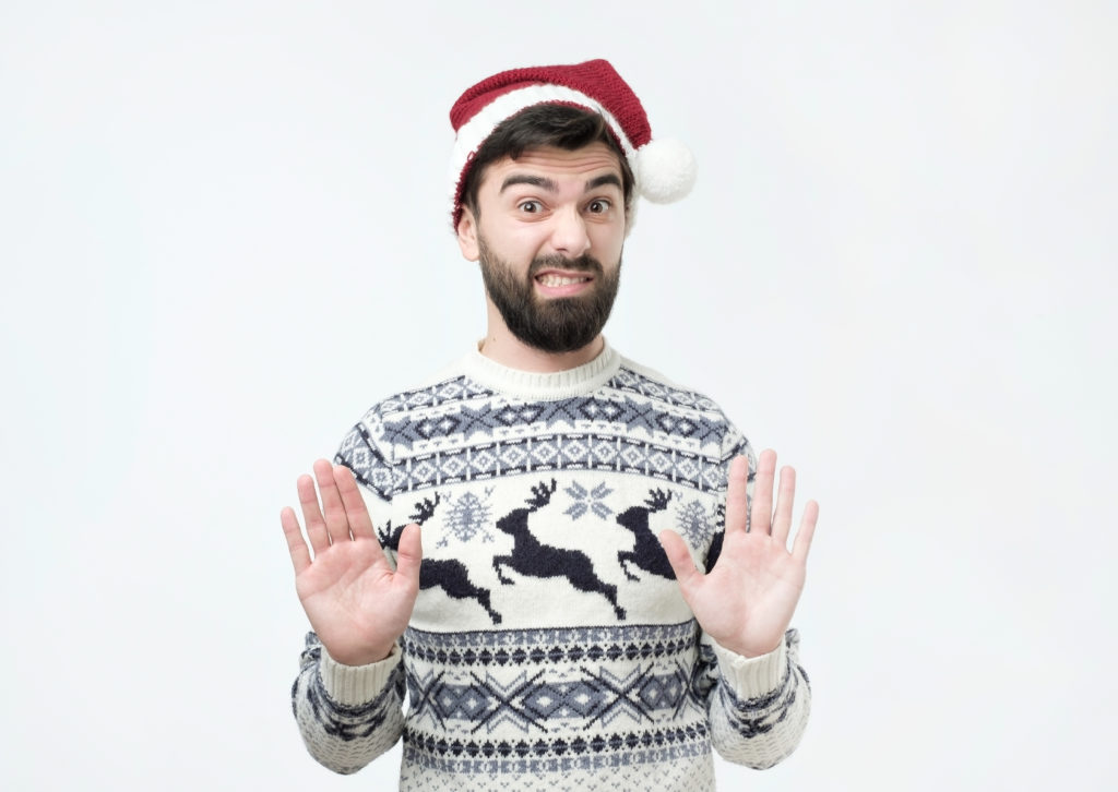 man wearing a santa hat with his hands up in protest to signal no