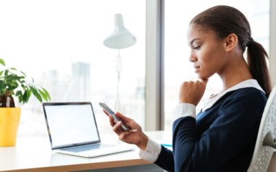 Business woman distracted by cellphone while working